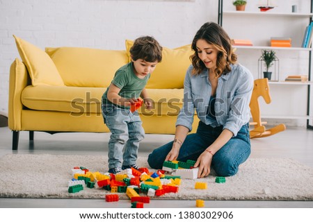 Mother and son playing with lego on carpet in living room
