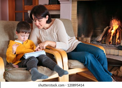 Mother and son playing on digital tablet PC  in front of fireplace - Powered by Shutterstock