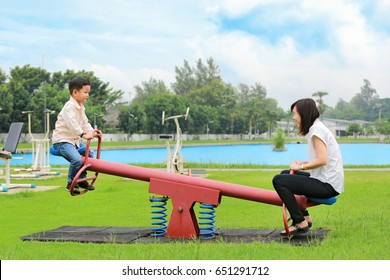 Mother with son playing seesaw in the park. - Powered by Shutterstock