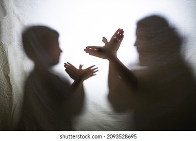 Mother   son playing and shadows behind bed sheet