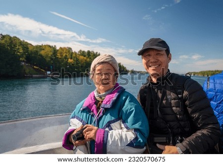 Mother and son posing for photo on cruise ship on Saint Lawrence river. Chinese tourists enjoying travel concept. Thousand Islands. Canada.