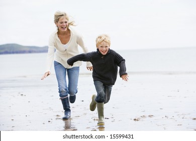 Mother And Son Running On Beach Smiling