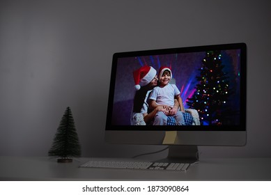 Mother and son in santa claus hats congratulate merry christmas on a video call on a computer