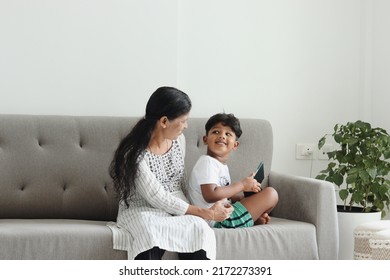 Mother And Son Sitting On The Sofa Using Ipad