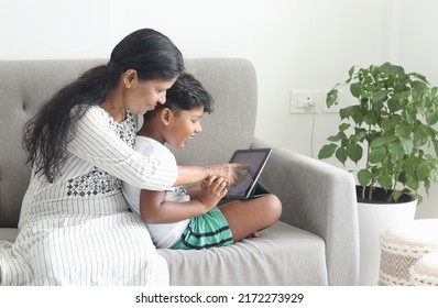 Mother And Son Sitting On The Sofa Using Ipad 