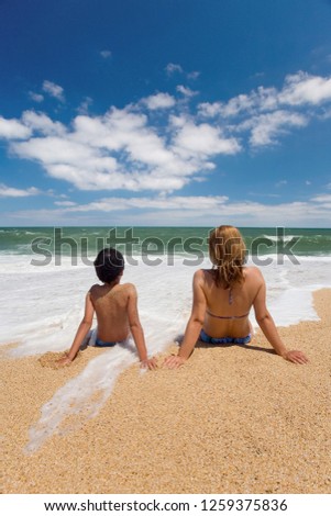Mother and son are sitting in the waves