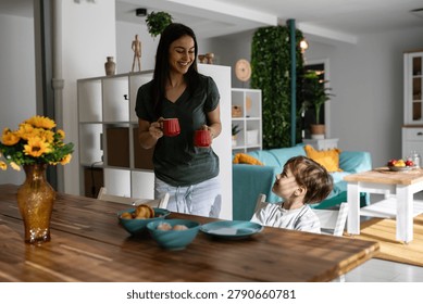 Mother and son smiling and interacting while having breakfast at the dining table, enjoying togetherness and happy morning