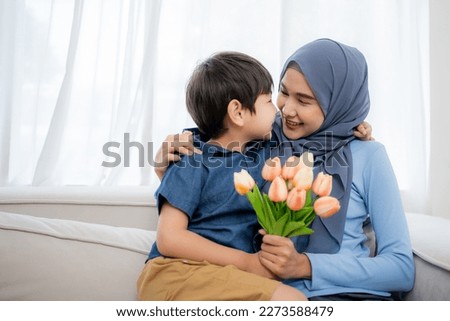 Mother and son spend time together and hugging gives a tulip flower on mother’s day together at home.