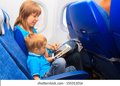 mother and son with touch pad in plane, family travel