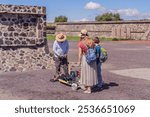 Mother and son tourists buying Mexican souvenirs from a street vendor at the foot of the Teotihuacan pyramid. Cultural experience, travel, and local craftsmanship concept