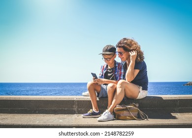 Mother And Son Using Smartphone Together. Smiling Kid And Mum  Taking Selfie. Family Enjoying Video Call With Friends On Mobile Phone. Technology, Lifestyle, Communication, Vacation And Travel Concept