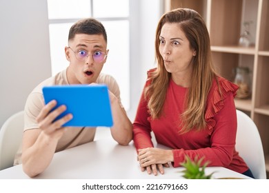 Mother And Son Using Touchpad Device Scared And Amazed With Open Mouth For Surprise, Disbelief Face 