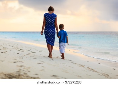 Mother And Son Walking On Sunset Beach