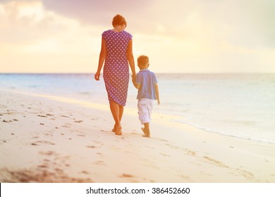 Mother And Son Walking On Sunset Beach