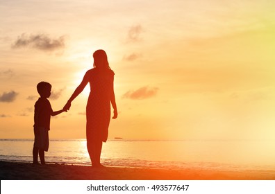 Mother And Son Walking On Sunset Beach