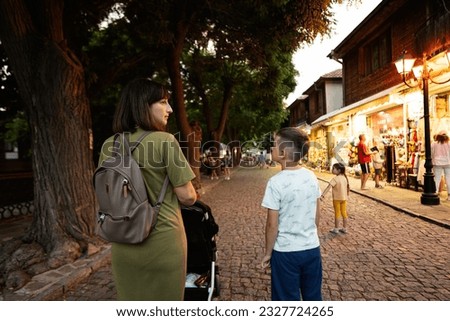 Mother and son walking through the streets of the old town Nessebar in summer evening.