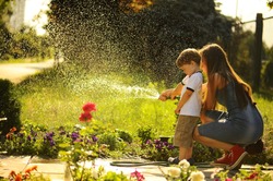 Mother And Son Watering The Lawn.