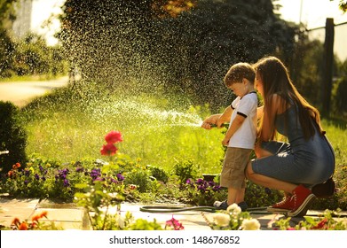 Mother And Son Watering The Lawn.