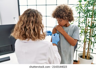 Mother And Son Wearing Doctor Uniform Putting Band Aid On Child Arm At Clinic