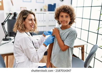 Mother And Son Wearing Doctor Uniform Putting Band Aid On Child Arm At Clinic