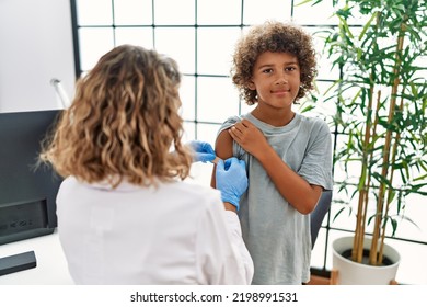 Mother And Son Wearing Doctor Uniform Putting Band Aid On Child Arm At Clinic