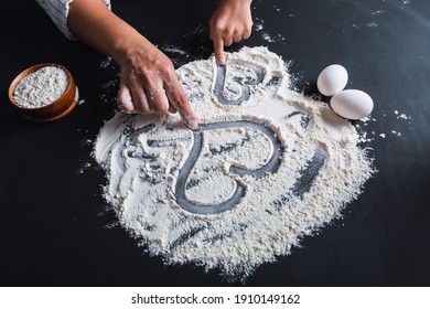 Mother And Son's Hands Drawing Hearts On The Flour.