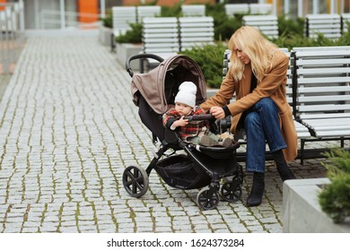 Mother Speaking With Her Small Daughter And Sitting On A Bench Outdoors