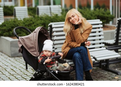 Mother Speaking With Her Small Daughter And Sitting On A Bench Outdoors