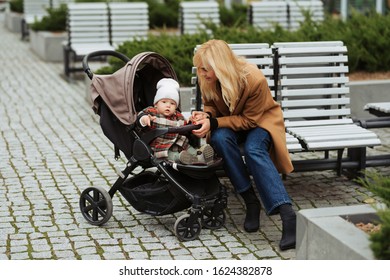 Mother Speaking With Her Small Daughter And Sitting On A Bench Outdoors