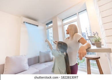 Mother in sportswear with daughter standing near the air conditioning