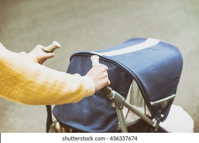Mother strolling with newborn in carriage. Closeup shot