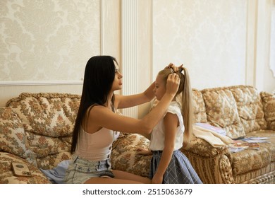 A mother styles her daughters hair in a cozy living room during the day - Powered by Shutterstock