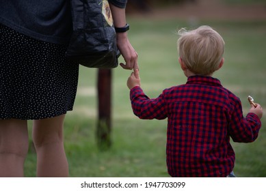 A Mother And Sun Walking Away From The Camera. Walking Hand In Hand.