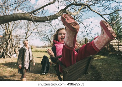 Mother swaying her daughter on a swing