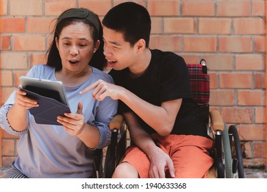 Mother Take Care Special Need Child On Wheelchair By Love, Boy Using Tablet With Parent By Excited Mood, Study At House Or Homeschool Concept, Change Home To Be A School And Parents Are Teachers.