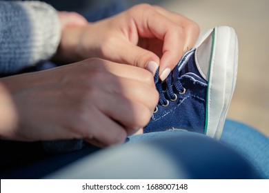 Mother taking care of her baby tying his shoe laces on sneakers - Powered by Shutterstock