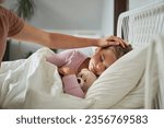 Mother taking care of her ill sleeping daughter at home