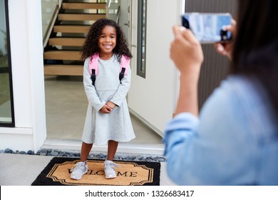 Mother Taking Photo Of Daughter With Cell Phone On First Day Back At School