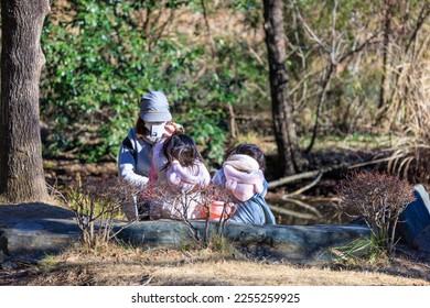 Mother taking a picture of her child sitting in winter park - Shutterstock ID 2255259925