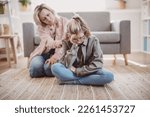 Mother taking pity on her daughter sitting on the floor. Concept of the family relation.