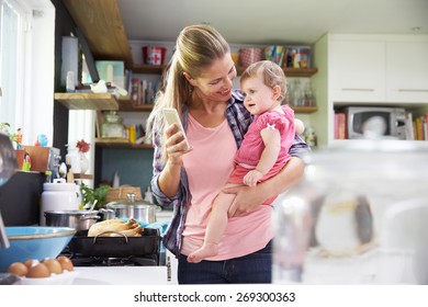 Mother Taking Selfie On Mobile Phone Holding Young Daughter