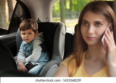 Mother Talking By Phone While Driving Car With Her Son On Backseat. Child In Danger