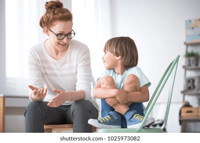 Mother talking to her smiling son sitting on green chair about school  - Shutterstock ID 1025973082