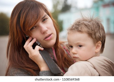 Mother talking on a smartphone with a baby on her hands while walking close-up. - Powered by Shutterstock