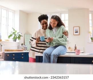 Mother Talking With Teenage Daughter At Home As She Checks Social Media On Mobile Phone - Powered by Shutterstock