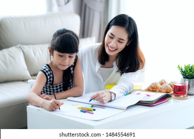 Mother teach Asian preschool student do homework by reawing by a color, this image can use for girl, study, school,mother, teacher, kid, student and education concept