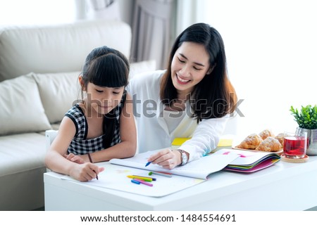 Mother teach Asian preschool student do homework by reawing by a color, this image can use for girl, study, school,mother, teacher, kid, student and education concept