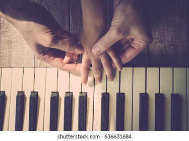 Mother teaches the daughter to play the piano. Concept Mother's Day. Female and children's hands. Vintage toning. Top view - Powered by Shutterstock