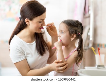 Mother teaches her child daughter accurately brushing teeth - Shutterstock ID 1609960441