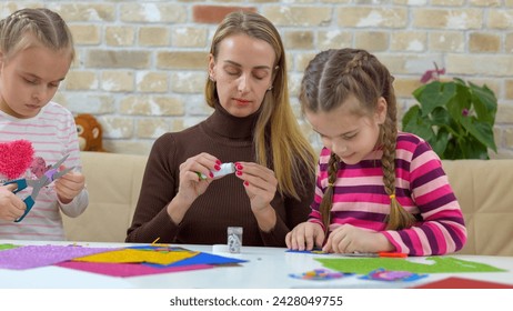 Mother teaches her children to do craft item from colored paper - Powered by Shutterstock